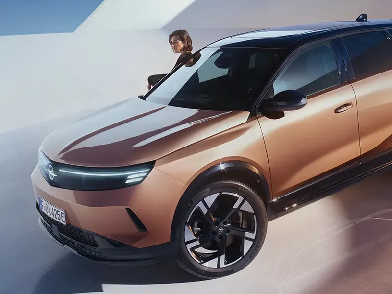 Opel Grandland in Kupfer-Metallic, daneben steht eine Frau